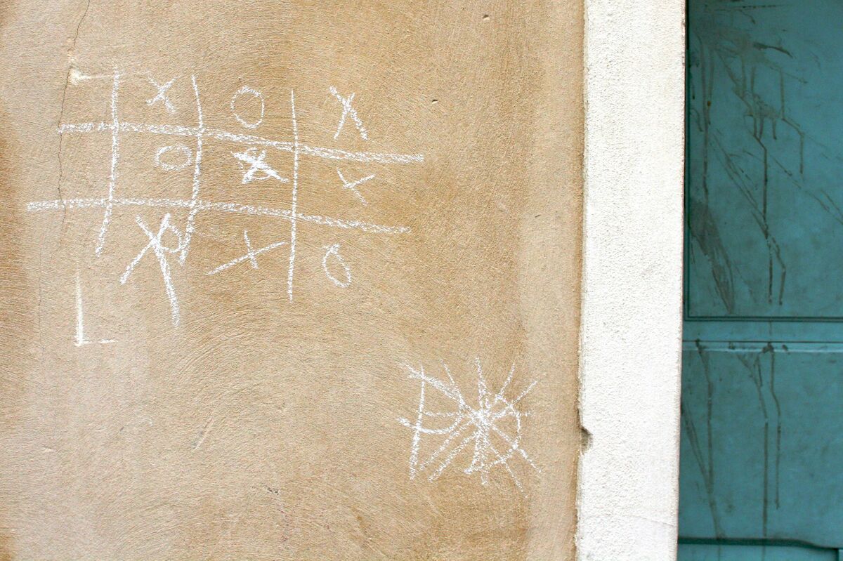 A wall with a completed tic-tac-toe game drawn on it in chalk.