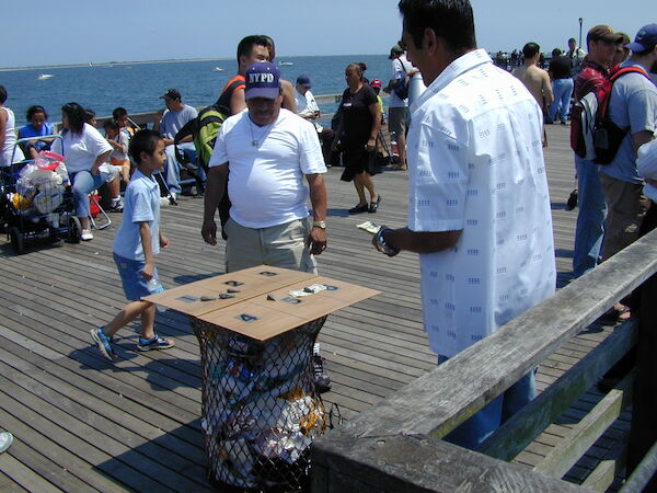 A man standing behind a Chuck-a-Luck board attempts to entice passers by.