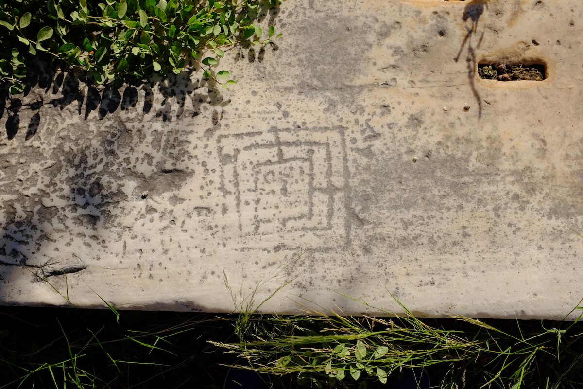 A weathered Nine Men’s Morris board scratched into a rock.