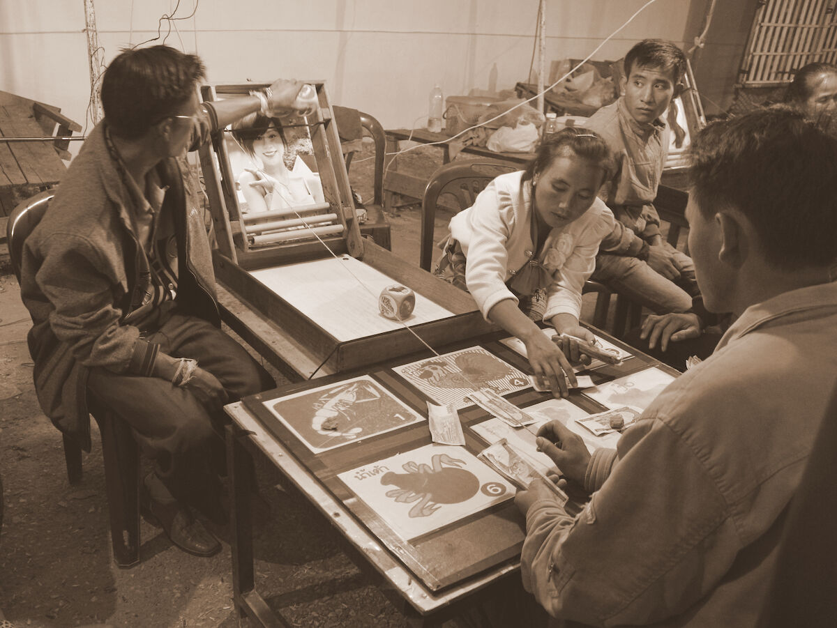 A man places a large die into a dice tower above a staking table.