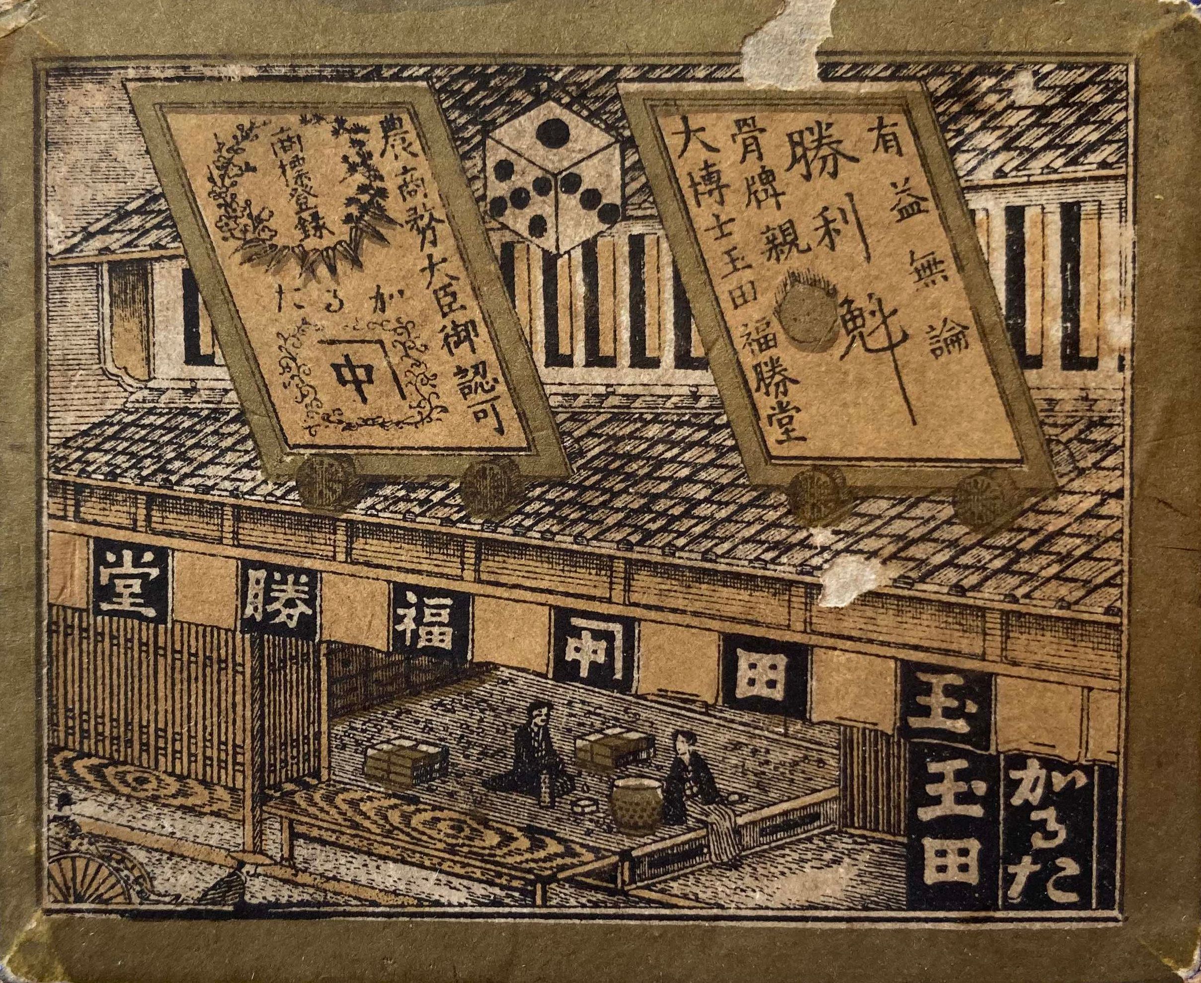 A box front depicting the storefront of a Japanese karuta manufacturer.