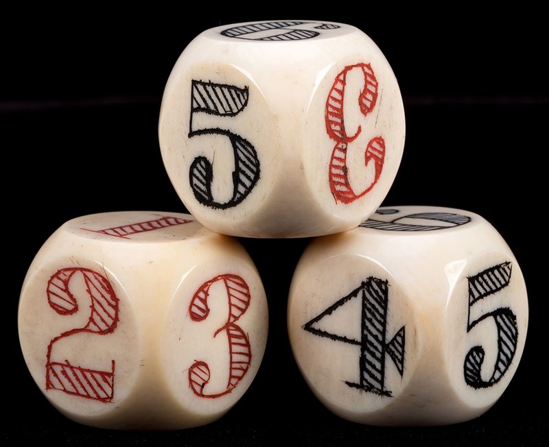 Three dice with the numbers 1 to 6 inscribed on their faces, with 1, 2, and 3 in red, and 4, 5, and 6 in black.
