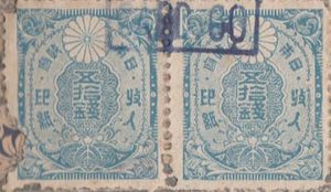 A square blue stamp reading ‘50 sen’ in Japanese with a stylized chrysanthemum flower.