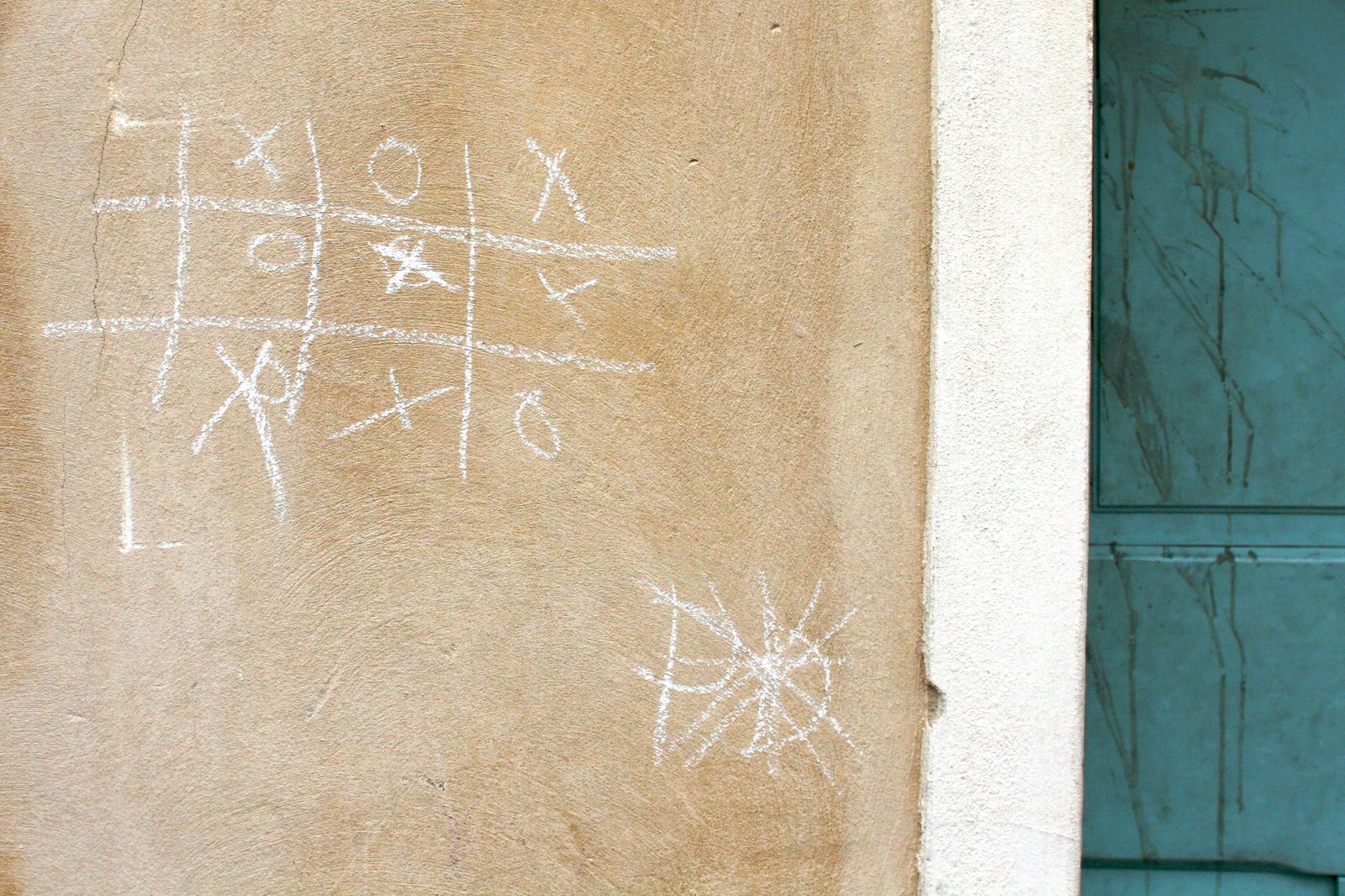 A wall with a completed tic-tac-toe game drawn on it in chalk.