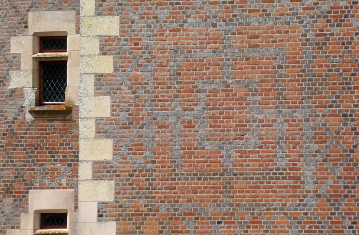 A Morris board in a brick wall, made out of black and red bricks
