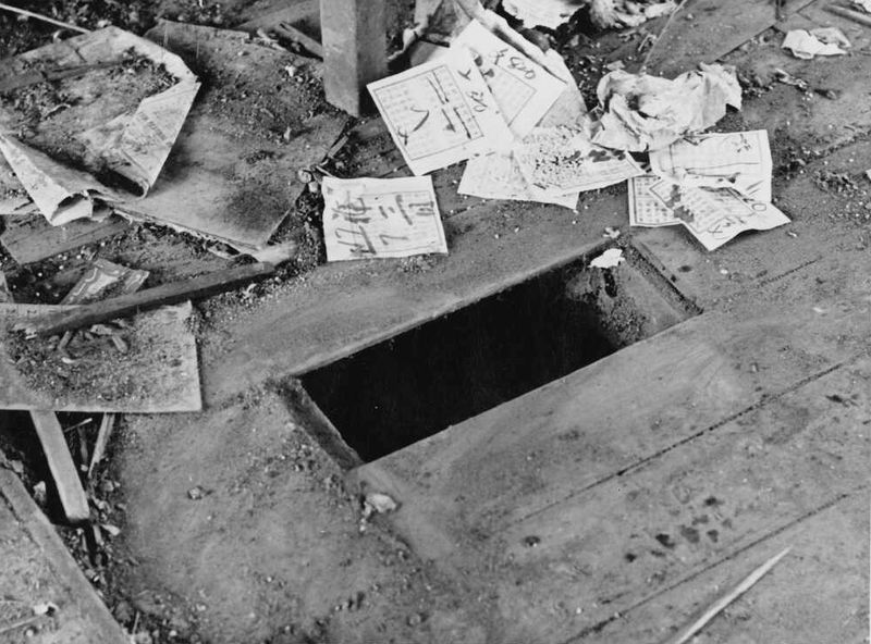A photograph of a dirty floor with a missing floorboard. Around the hole lie used tickets.