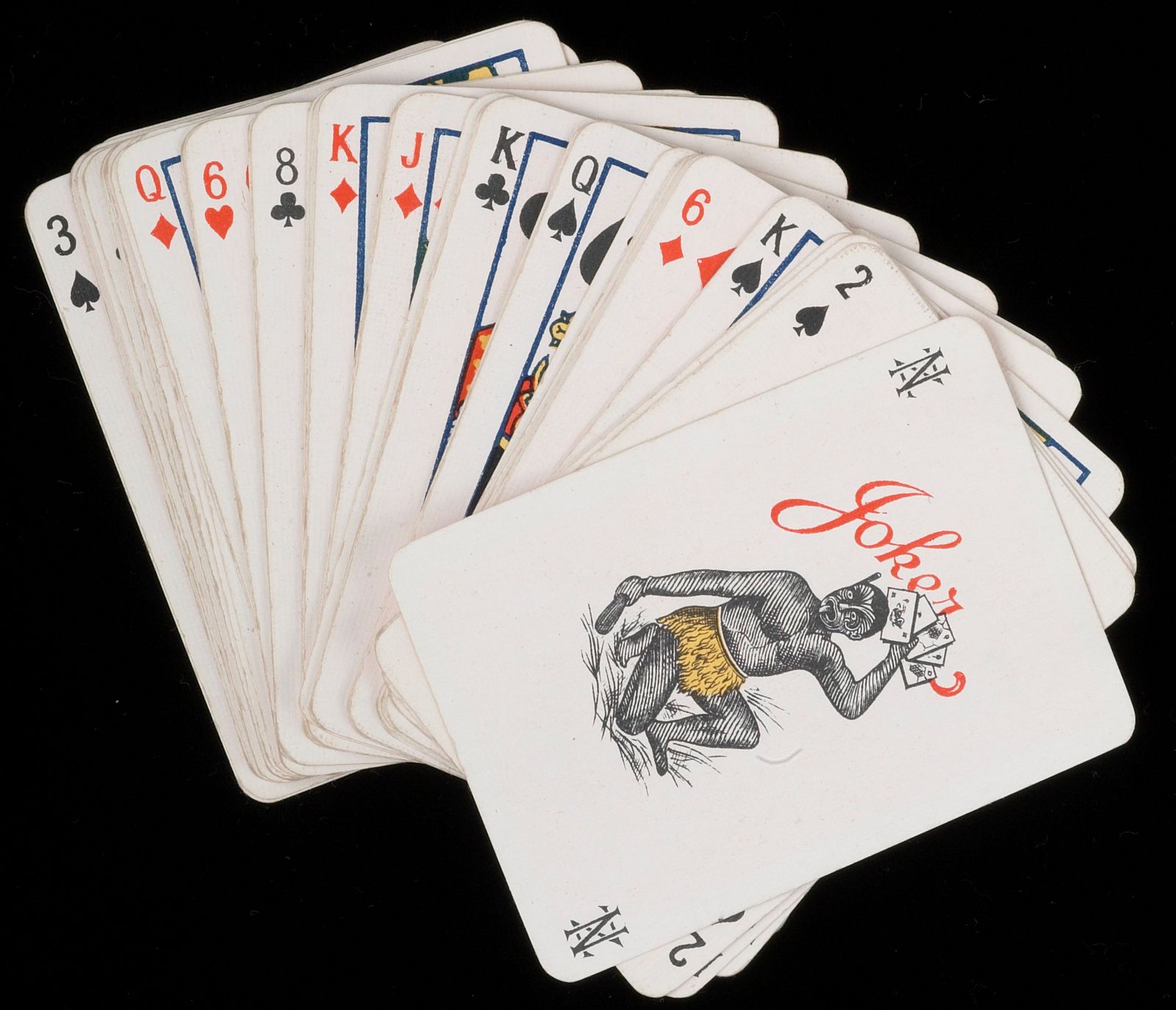 A spread of playing cards with joker on top. The joker has an image of a Māori warrior flourishing playing cards.